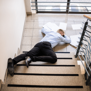 Man on the floor after falling down the stairs at work also known as a Slip and Fall Accident.